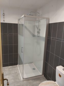 Douche moderne installée dans une salle de bain entièrement rénovée. Les finitions sont soignées, avec un receveur extra-plat et un carrelage mural élégant, réalisés par WT TOUS TRAVAUX à Montbéliard