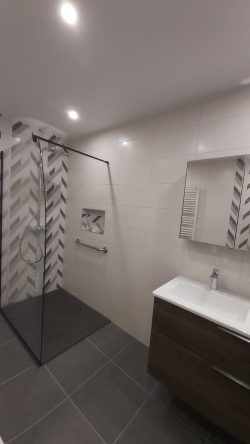 À Belfort, cette salle de bain a été repensée pour allier esthétisme et confort : douche de plain-pied, barre de maintien, niche intégrée et mobilier moderne.